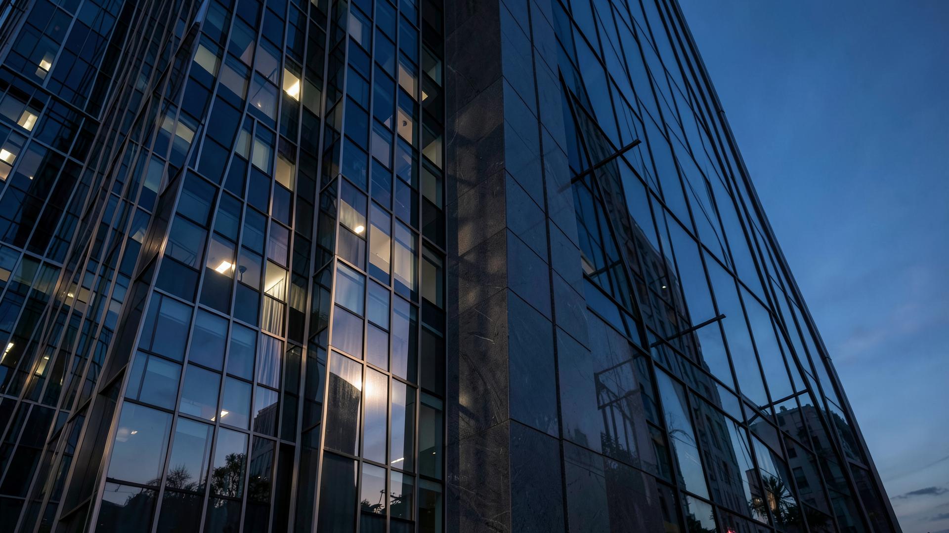 Dusk light raking across a glass and steel high-rise facade